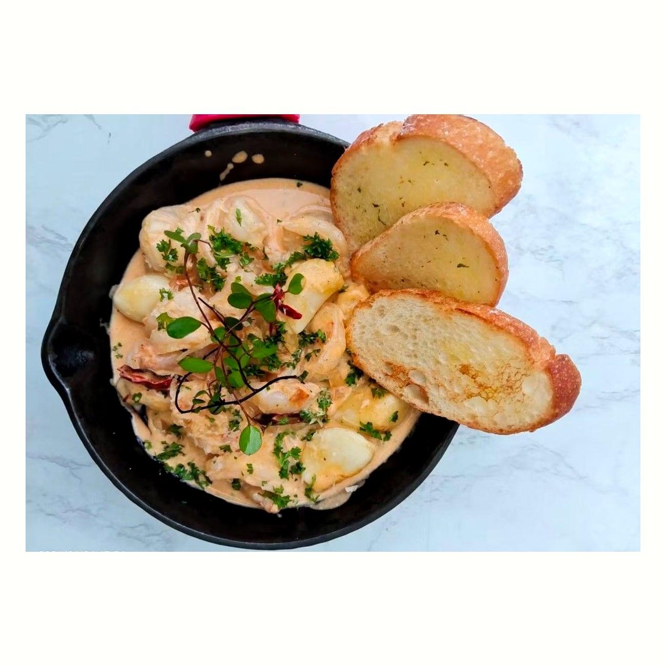 Creamy seafood skillet with toasted baguette at Justgrapes